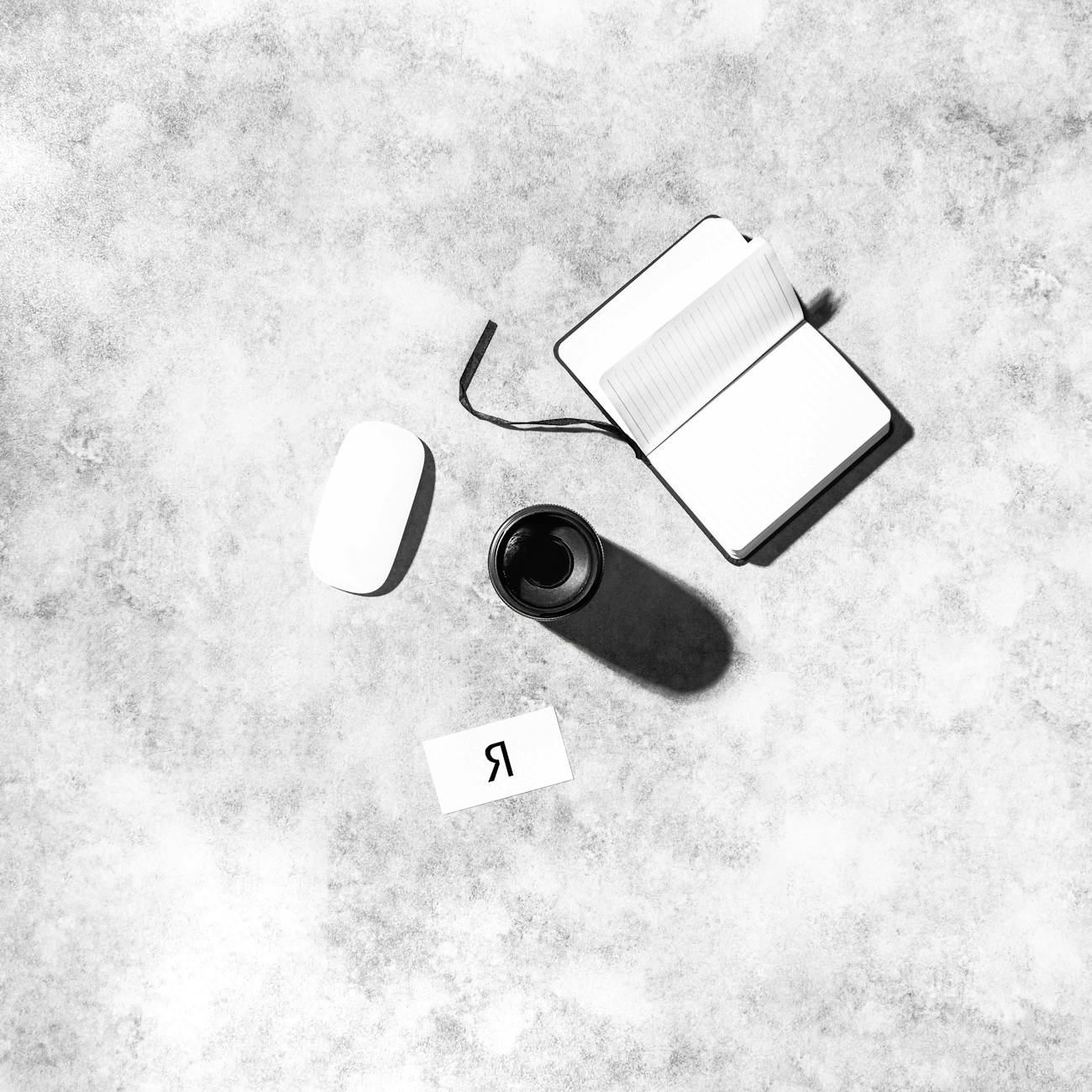 A minimalist workspace featuring a notepad, coffee cup, and accessories.