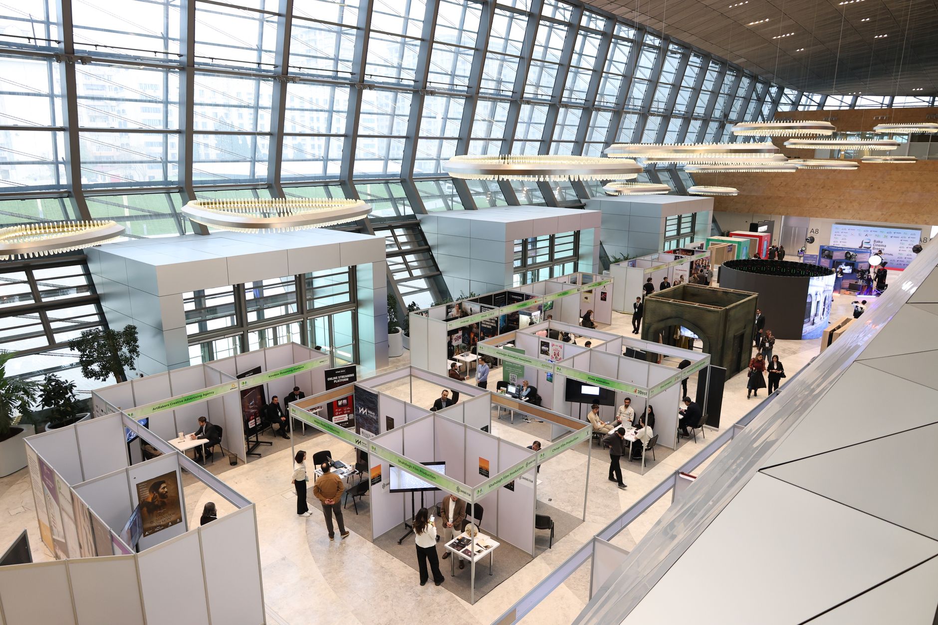 A trade show exhibition hall with people networking near display booths.